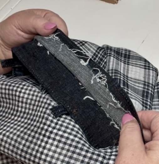 hands holding an upcycled denim waistband that is opened up so that the front of the jacket can be inserted